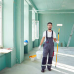 Bearded painter smiling construction worker with tools on a construction site.