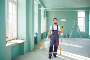 Bearded painter smiling construction worker with tools on a construction site.